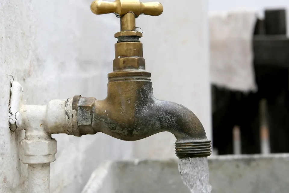 Old brass faucet with water running from it